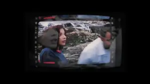 A candid scene of two people in front of a rocky backdrop, captured with a vintage film frame effect.