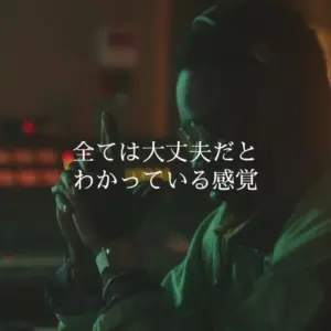 A person in a dimly lit room holding a camera, emphasizing focus and creativity, with Japanese text overlay.