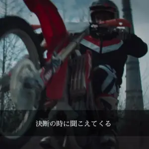 A rider performs a thrilling wheelie on a red dirt bike amidst a dramatic landscape.