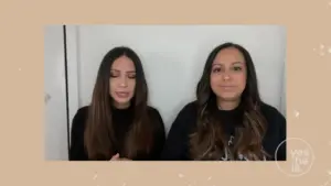 Women discussing a topic, seated against a neutral background, showcasing engagement and collaboration.