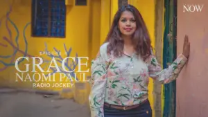 Naomi Paul, a radio jockey, poses in front of a vibrant yellow wall, showcasing her style and confidence.