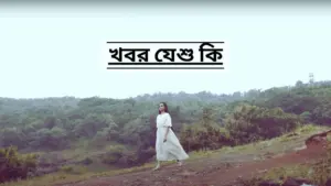 A woman in a flowing white dress walks through a scenic landscape, with greenery and hills in the background.