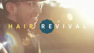 Smiling man outdoors with glasses, showcasing a vibrant sunset and the text "Hair Revival" prominently displayed.