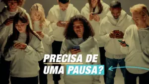 Group of young people in white hoodies looking at their phones, suggesting the need for a break with the text "Precisa de uma pausa?"