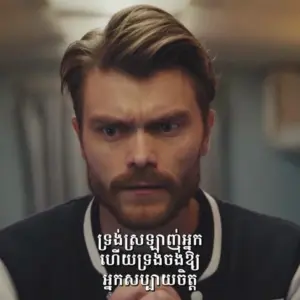 A focused man with a beard looks intently while text appears in a stylized font on the screen.