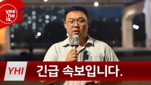 Man speaking into a microphone at night with a city backdrop, featuring the text "긴급 속보입니다." in red.