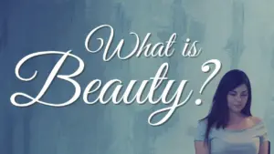 A contemplative woman stands before a soft, abstract background, pondering the question, "What is Beauty?"