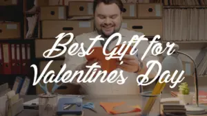 Smiling man holding a Valentine's Day gift, surrounded by colorful craft supplies and a cheerful workspace.