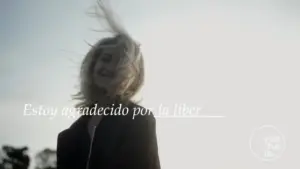 Smiling woman with flowing hair against a bright sky, expressing gratitude and joy in a candid moment.