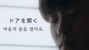 Close-up of a person's face with soft lighting, featuring Japanese text encouraging open-mindedness and self-reflection.