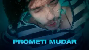 Man submerged underwater with hair flowing, wearing a striped shirt, surrounded by bubbles and a blue tint.