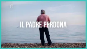 A man in a hooded sweatshirt stands by the calm sea, gazing into the distance with the title "Il Padre Perdona" overlayed.