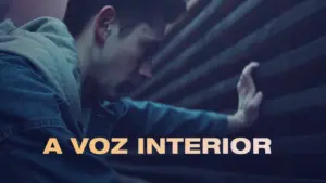 A man touching a textured surface, reflecting introspection, with "A Voz Interior" text in bold letters.