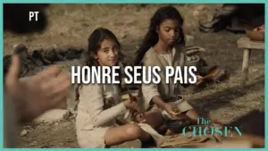 Two young girls sitting on the ground, engaged in crafts, with a rustic background from "The Chosen" series.