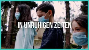 Three children wearing masks walk outdoors among trees, with the phrase "In unruhigen Zeiten" prominently displayed.