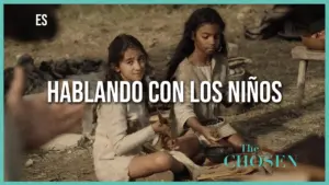 Two girls engaged in conversation while sitting on the ground, surrounded by simple items, from "The Chosen" series.