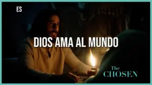 A scene from "The Chosen" featuring a man discussing love and faith by candlelight with the text "Dios ama al mundo."