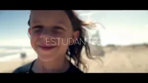 Smiling student with wind-swept hair on a sunny beach, capturing joy and adventure in a vibrant outdoor setting.