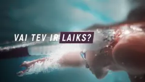 Person swimming underwater with text overlay asking, "Vai tev ir laiks?" in a vibrant, energetic atmosphere.