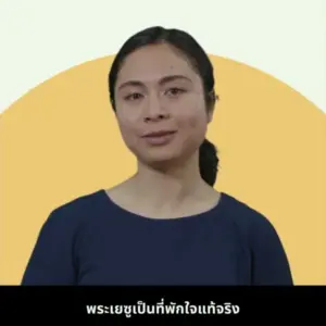 A woman speaking confidently against a graphic background, conveying an inspiring message in Thai.