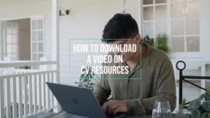 Person using a laptop while downloading a video on CV resources outside a bright, cozy setting.