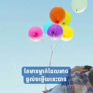 Person holding colorful balloons against a clear blue sky, with vibrant hues creating a cheerful atmosphere.