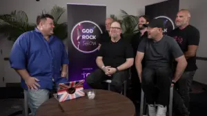 Group of entertainers smiling together at the God Rock Show, with a vibrant backdrop and a laptop on the table.