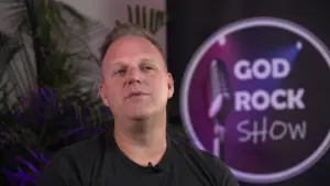 Host of the God Rock Show with a microphone backdrop, creating a vibrant atmosphere for music and entertainment.