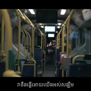 Interior of a city bus with empty seats and yellow handrails, showcasing a modern public transport environment.