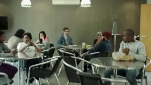 Group of diverse people sitting at tables in a modern café, enjoying food and engaging in conversation.