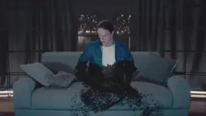 A woman in a blue jacket sits on a couch with dark particles flowing from her, set against a city skyline at night.