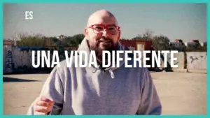 Man with glasses smiling outdoors, promoting a positive message about living a different life.