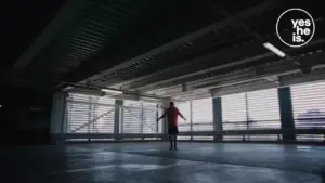 Person jumping in a spacious, brightly lit industrial environment with large windows and a modern aesthetic.