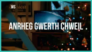 Colorful Christmas tree with lights beside a television displaying a starry night sky. Text overlay in Welsh language.