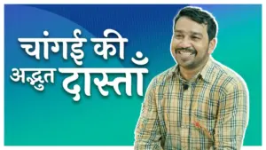 Smiling man in a checkered shirt against a colorful background with text in Hindi meaning "Amazing Stories of Change."