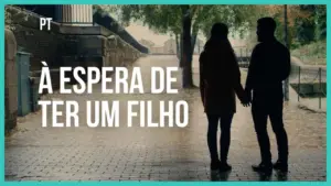 Silhouetted couple holding hands under trees, with the text "À espera de ter um filho" prominently displayed above.