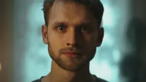 Close-up of a young man with a thoughtful expression, soft lighting, and a blurred background, conveying introspection.