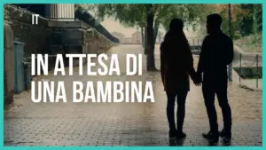 Couple holding hands under trees, with text "In attesa di una bambina" emphasizing anticipation and connection.