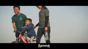 Family enjoying outdoor activities, with a child riding a bike while parents smile in a sunny, clear environment.