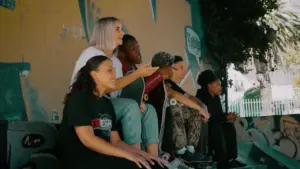 Group of diverse skaters enjoying a sunny day, sharing laughs and tips, in a vibrant urban skatepark setting.