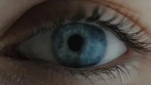 Close-up of a blue eye with intricate details, showcasing the cornea and eyelashes for a striking visual effect.