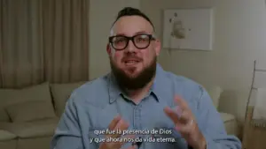 Man with glasses passionately speaking in a cozy indoor setting, discussing spirituality and eternal life.