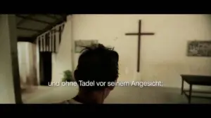 Person standing in a church interior with a cross on the wall, conveying a sense of reverence and spirituality.