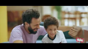 Father and son sharing a joyful moment, smiling together in a cozy living room setting.