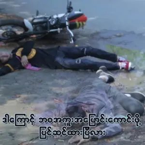 Scene of a motorcycle accident with two individuals lying on the ground, highlighting the aftermath of the crash.