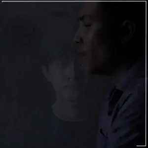 Two men in a dimly lit setting, one in focus and the other appearing as a ghostly reflection, creating a haunting atmosphere.