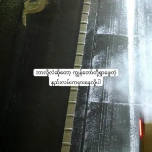 Aerial view of a wet road with tire tracks, reflecting light in a nighttime urban setting.