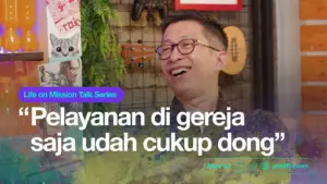 Smiling man in glasses surrounded by colorful decor, discussing church service in a lively talk show setting.