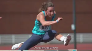 Female athlete competing in a hurdle race, showcasing determination and athleticism on a track.