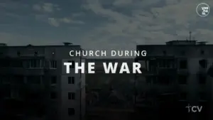 A somber view of a church surrounded by war-torn buildings under a cloudy sky, depicting resilience in conflict.